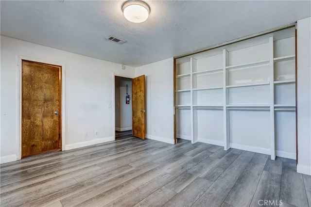 a view of an empty room with wooden floor and closet