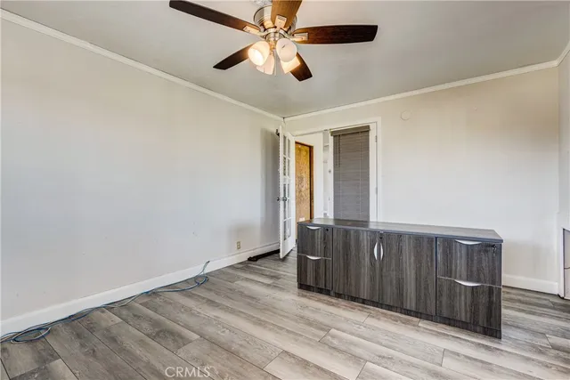 an empty room with wooden floor fan and windows