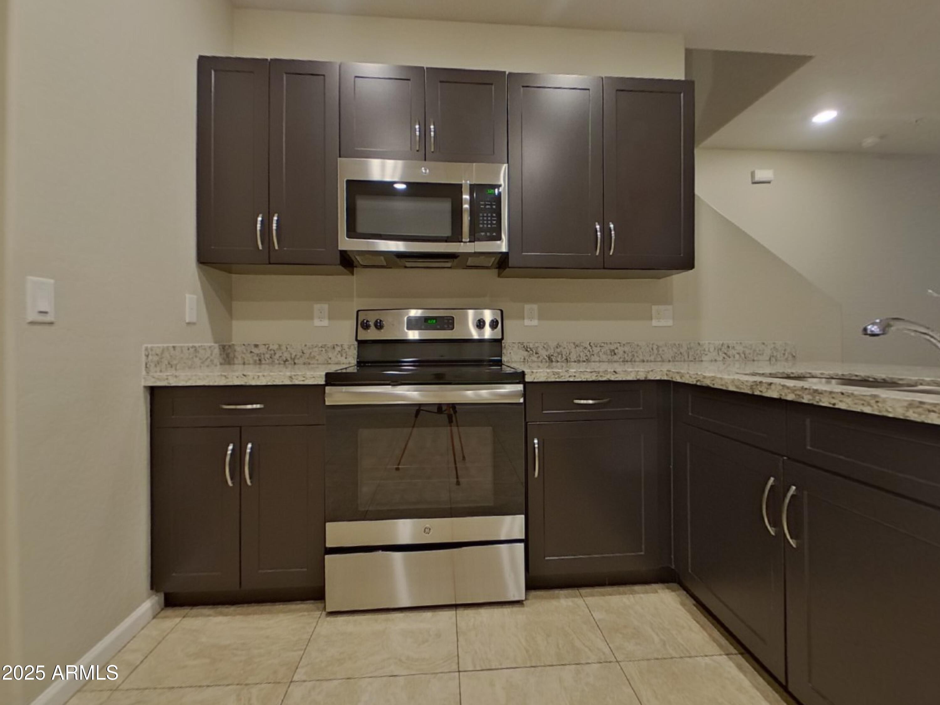 12578 West Steed Ridge Peoria, AZ 85383 - Photo 4 of 17 a kitchen with stainless steel appliances granite countertop a sink and a microwave