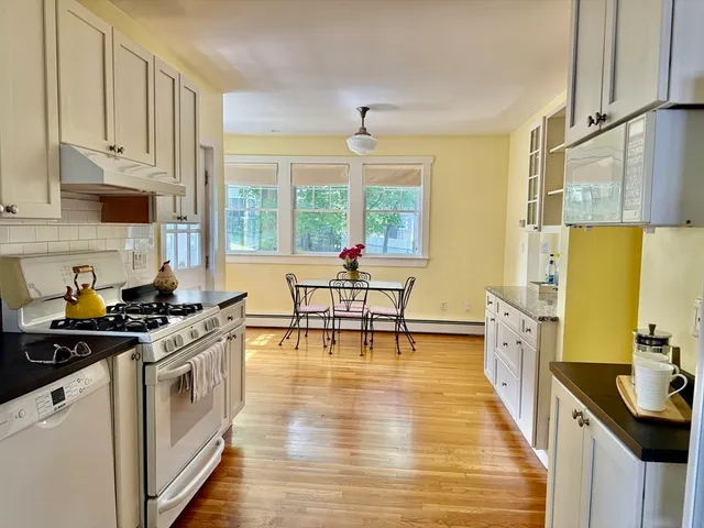 a kitchen with stainless steel appliances a stove a sink and white cabinets with wooden floor