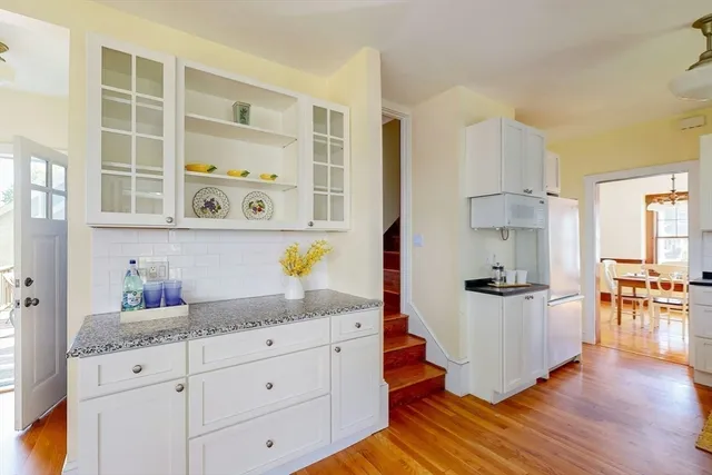 a kitchen with granite countertop a white cabinets and wooden floor