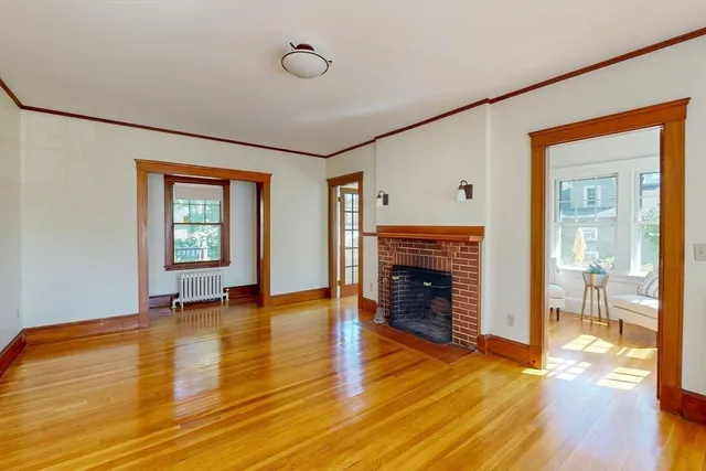 an empty room with wooden floor fireplace and windows