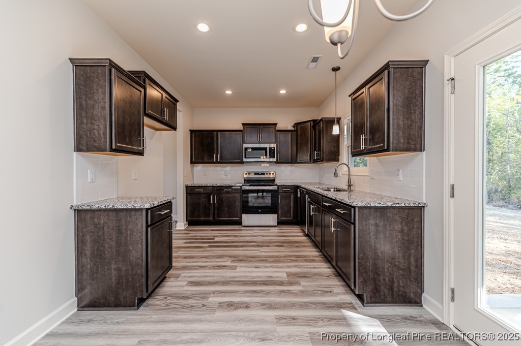 87 Onslow Court Spring Lake, NC 28390 - Photo 13 of 33 a large kitchen with stainless steel appliances wooden cabinets a stove and a sink