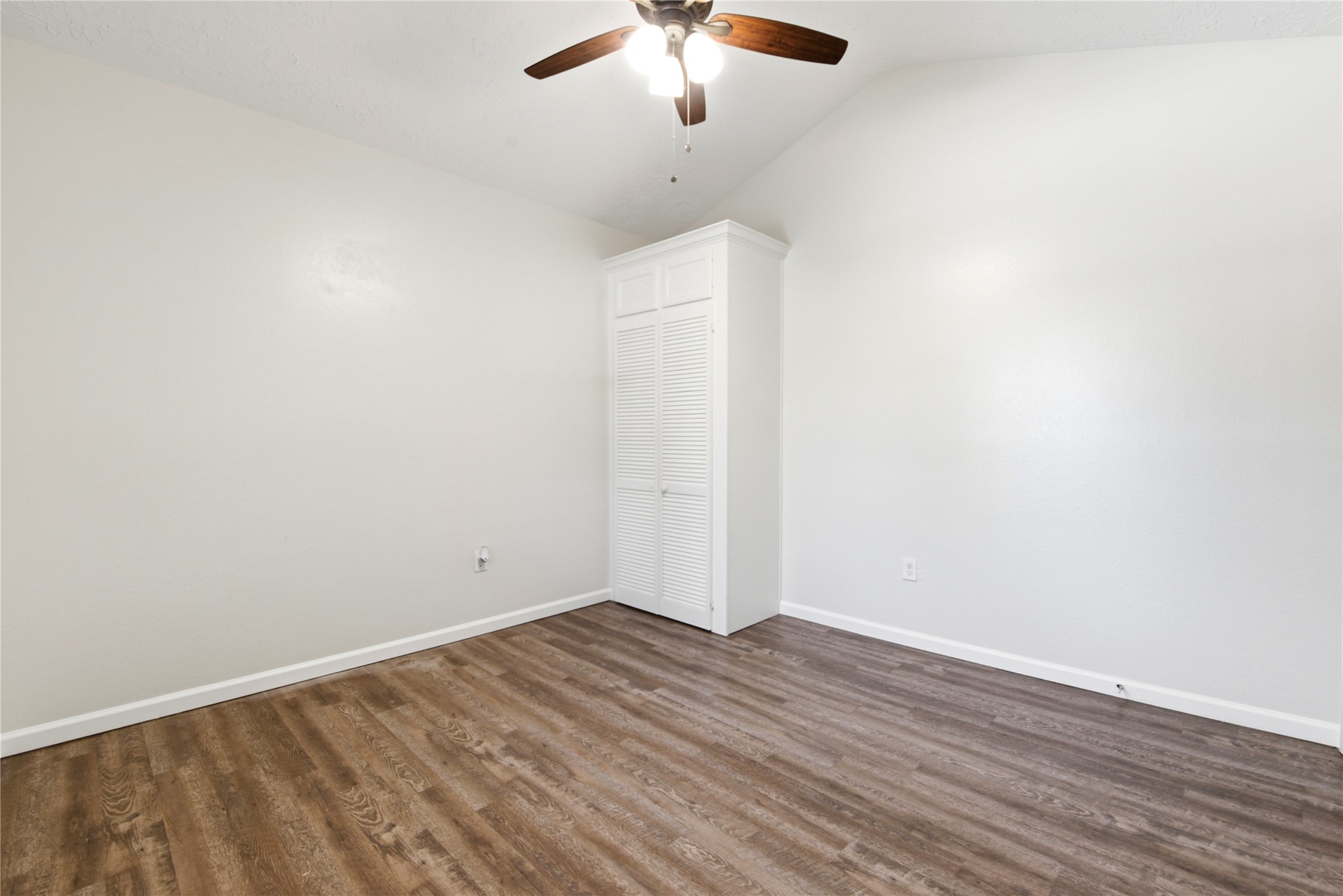 9403 Spaulding Street Houston, TX 77016 - Photo 27 of 50 This photo shows a bright room with neutral walls, wood-style flooring, a ceiling fan, and a built-in closet. Ideal for a bedroom or office.
