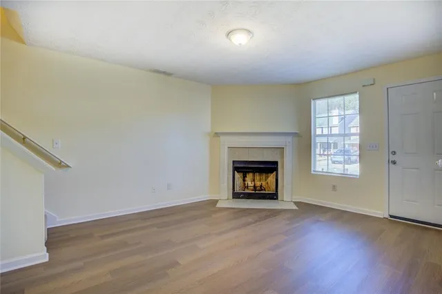 an empty room with wooden floor a fireplace and windows