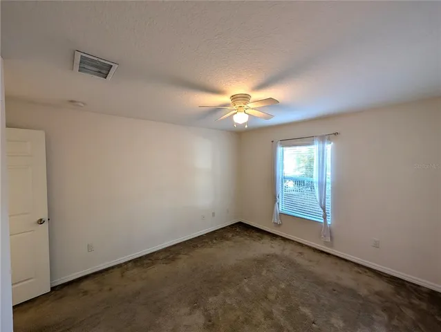 an empty room with a chandelier fan and windows