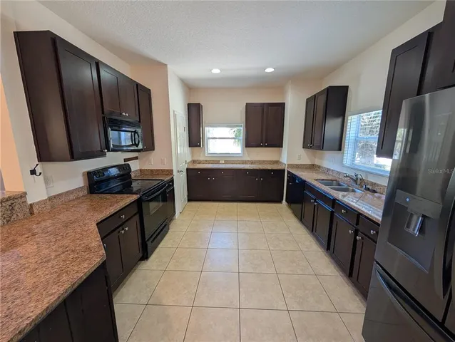a large kitchen with stainless steel appliances granite countertop a sink stove and refrigerator