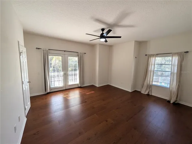 a view of empty room with wooden floor and fan