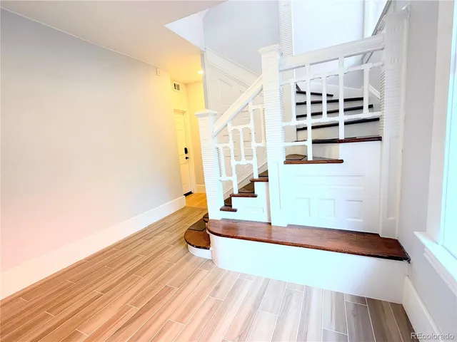 a view of an empty room with wooden floor fireplace and a window