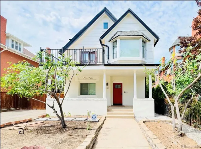 a view of a white house with a small yard and plants