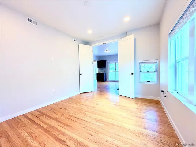 a view of empty room with window and wooden floor