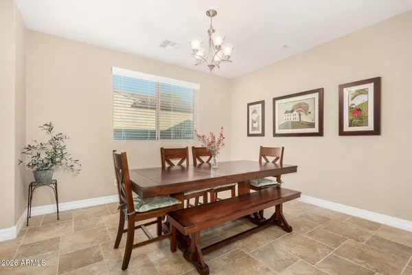 a kitchen with stainless steel appliances granite countertop a refrigerator a stove a sink a dining table and chairs with wooden floor