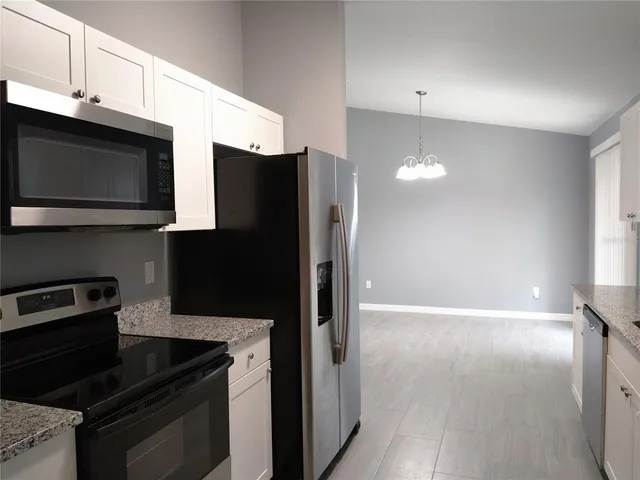 a kitchen with granite countertop a refrigerator and a stove top oven