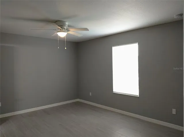 an empty room with a window and a fan