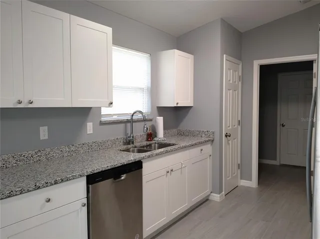 a kitchen with granite countertop white cabinets and a sink