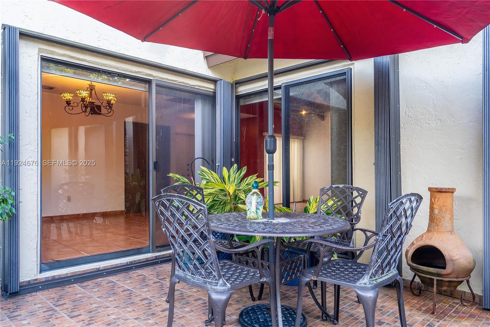 13585 Southwest 114th Terrace Miami, FL 33186 - Photo 35 of 42 a patio with a table and chairs under an umbrella