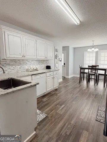 a kitchen with stainless steel appliances granite countertop a white cabinets and wooden floors
