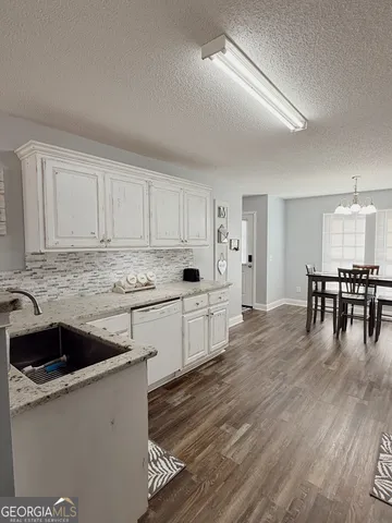 a kitchen with stainless steel appliances granite countertop a white cabinets and wooden floors