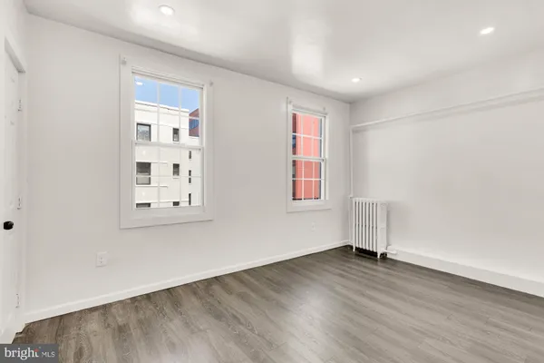 a kitchen with granite countertop a stove a sink and white cabinets with wooden floor