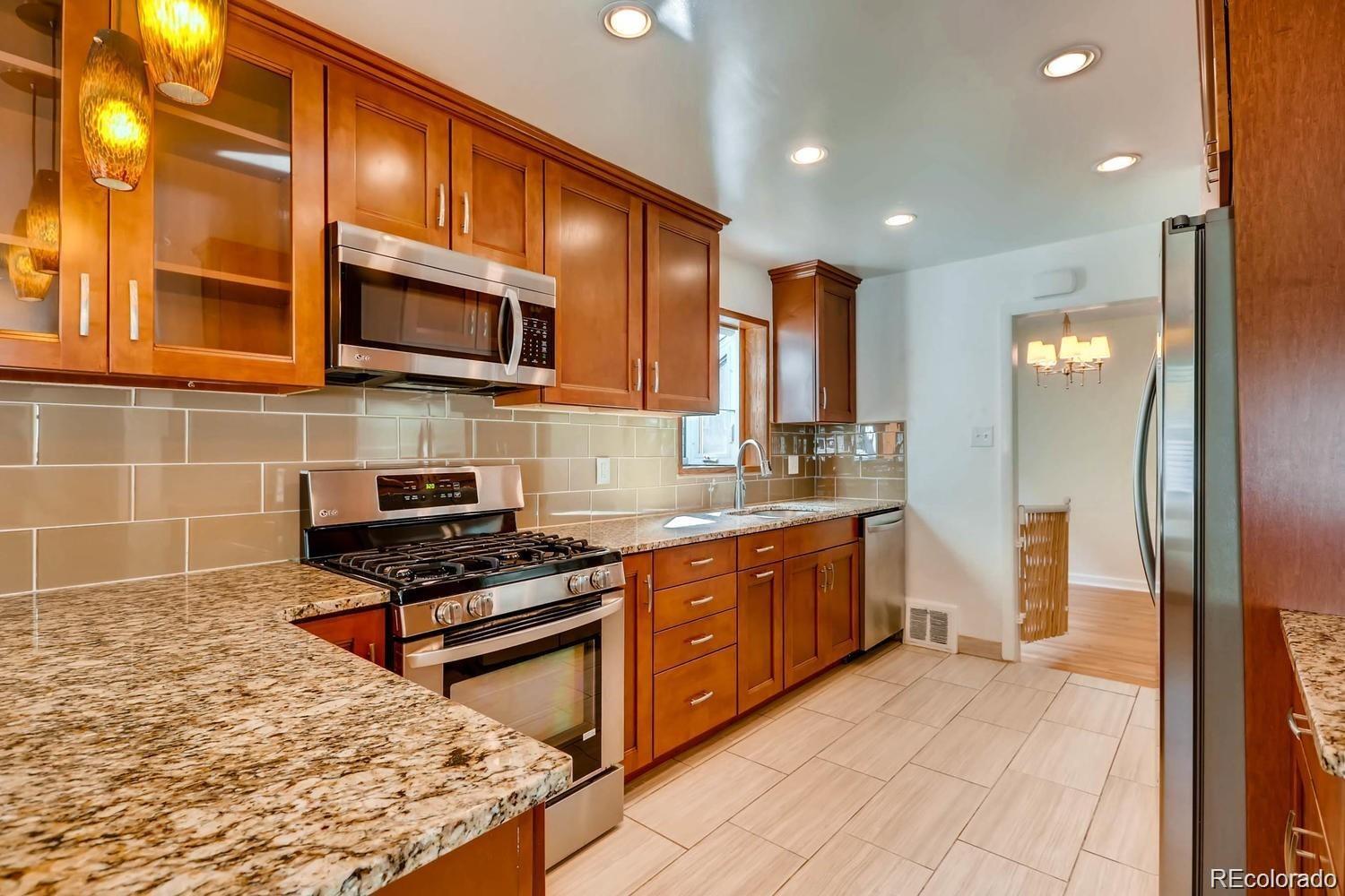 1610 South Cook Street Denver, CO 80210 - Photo 5 of 37 a kitchen with stainless steel appliances granite countertop a stove a sink and a microwave