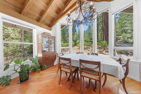 a living room with furniture a fireplace a flat screen tv and floor to ceiling window