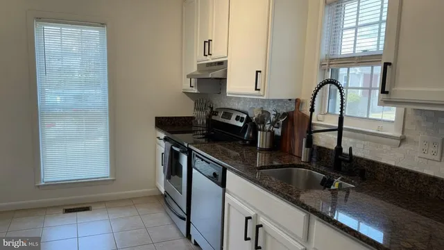 a kitchen with granite countertop a sink a stove and cabinets