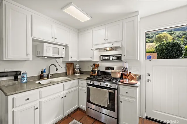 a kitchen with stainless steel appliances granite countertop white cabinets a stove a sink and dishwasher