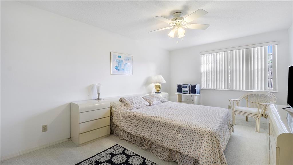 17210 Boca Club Boulevard, Unit 103 Boca Raton, FL 33487 - Photo 12 of 15 a bedroom with a bed and a chandelier