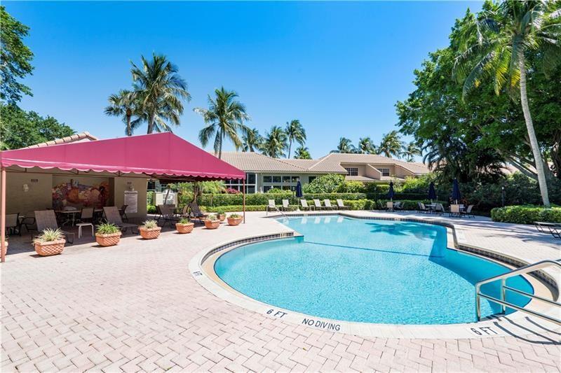 17210 Boca Club Boulevard, Unit 103 Boca Raton, FL 33487 - Photo 15 of 15 a view of a swimming pool with lawn chairs under an umbrella