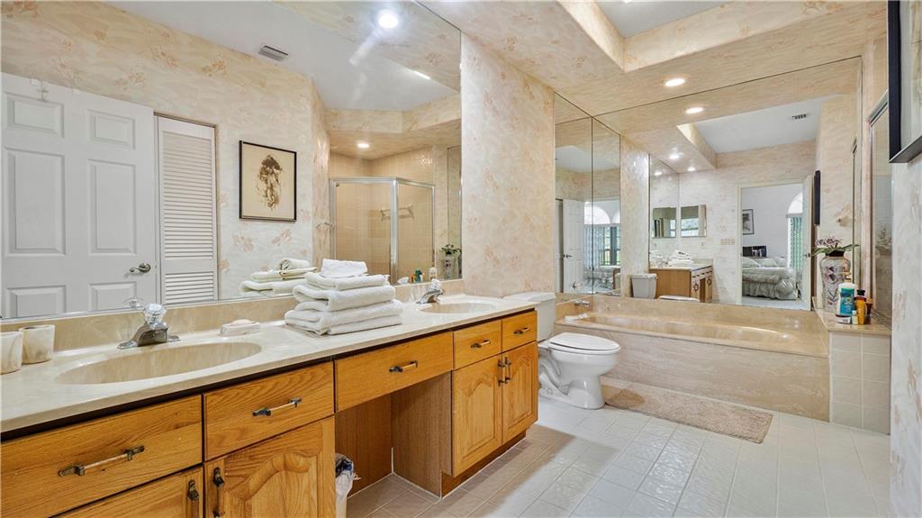 17210 Boca Club Boulevard, Unit 103 Boca Raton, FL 33487 - Photo 8 of 15 a bathroom with a double vanity sink toilet mirror and bathtub