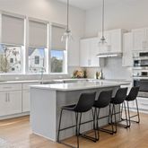 a kitchen with stainless steel appliances granite countertop a stove a sink a refrigerator and white cabinets with wooden floor