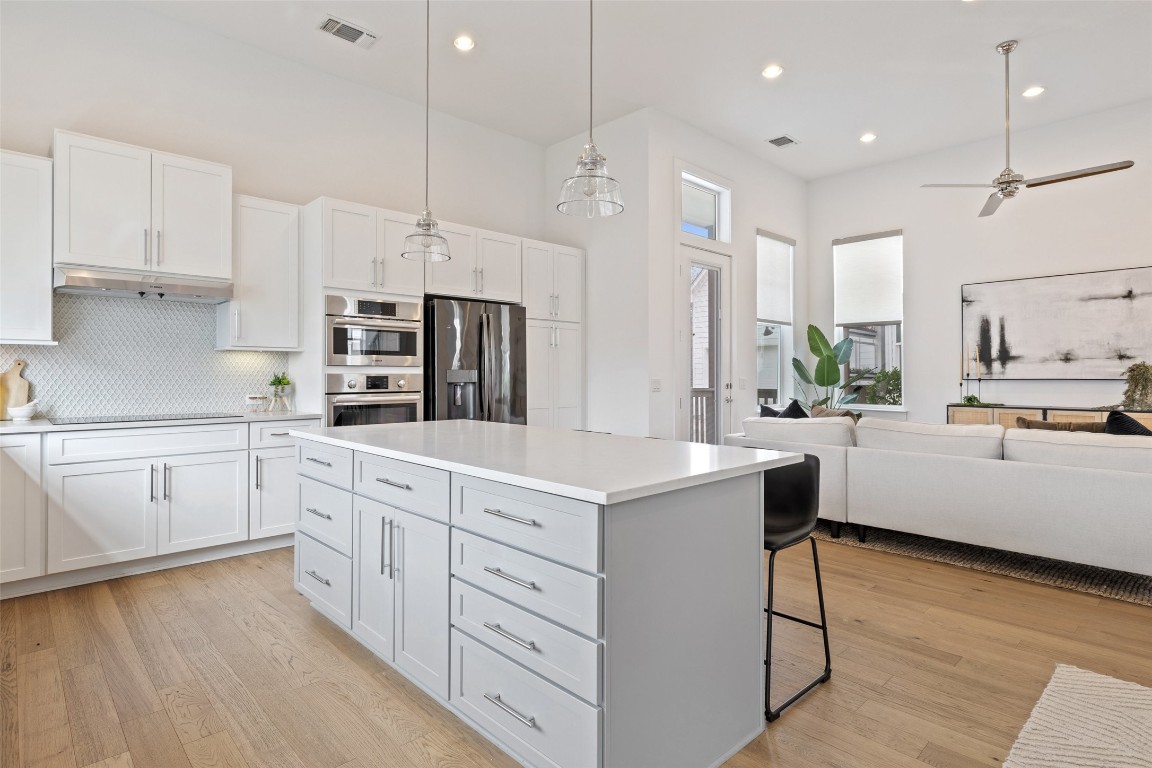 4400 Night Owl Lane Austin, TX 78723 - Photo 12 of 40 a large kitchen with stainless steel appliances kitchen island white cabinets and wooden floor