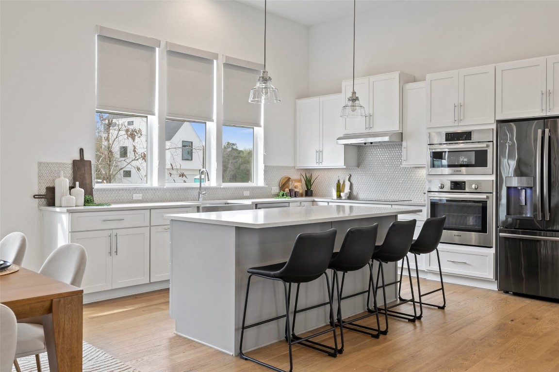 4400 Night Owl Lane Austin, TX 78723 - Photo 8 of 40 a kitchen with stainless steel appliances granite countertop a stove a sink a refrigerator and white cabinets with wooden floor