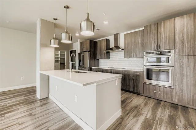 a large kitchen with stainless steel appliances granite countertop a sink a stove and a wooden floors