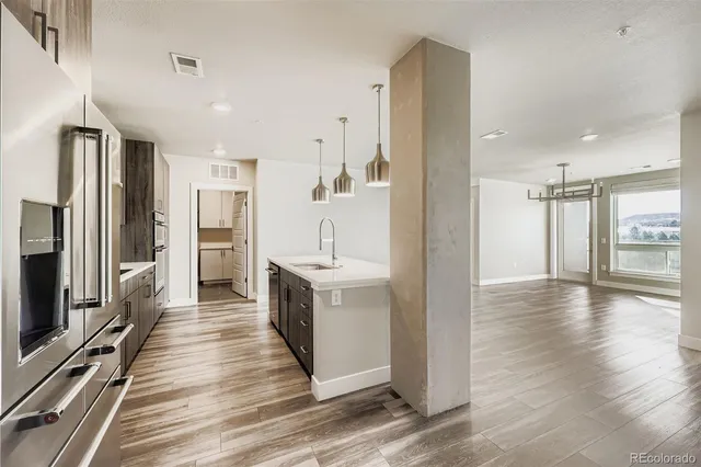 a view of a kitchen center island wooden floor and stainless steel appliances