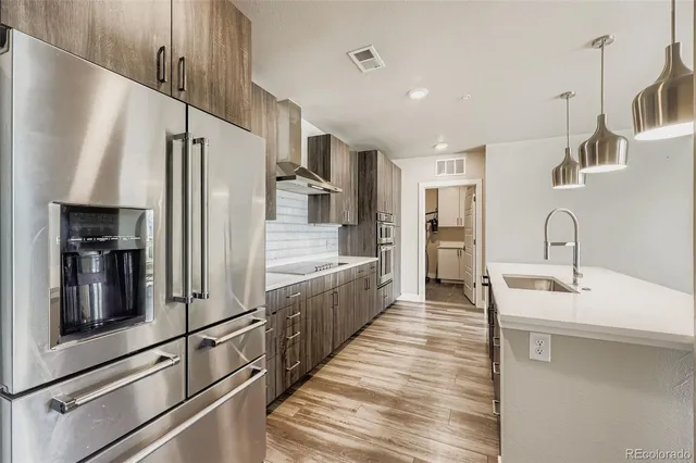 a large kitchen with stainless steel appliances a refrigerator a sink and white cabinets