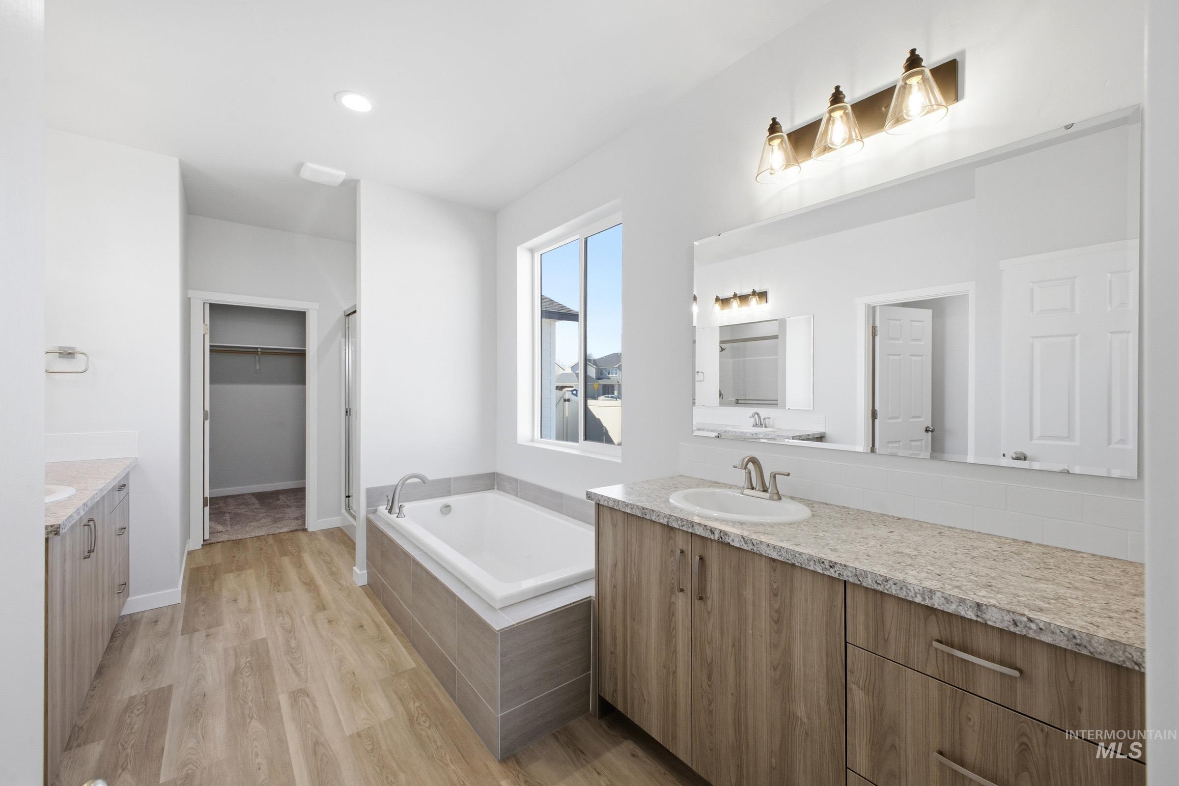 13633 Redway Court Caldwell, ID 83607 - Photo 24 of 29 Bathroom featuring two vanities, a bath, light wood-style flooring, and a spacious closet
