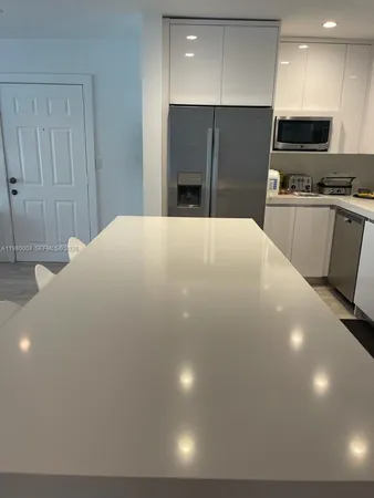 a large white kitchen with stainless steel appliances a refrigerator and a microwave