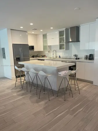 a kitchen with stainless steel appliances kitchen island granite countertop a stove a sink a dining table and chairs with wooden floor