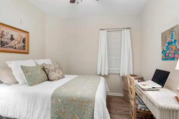 a bedroom with a bed and furniture with computer on desk