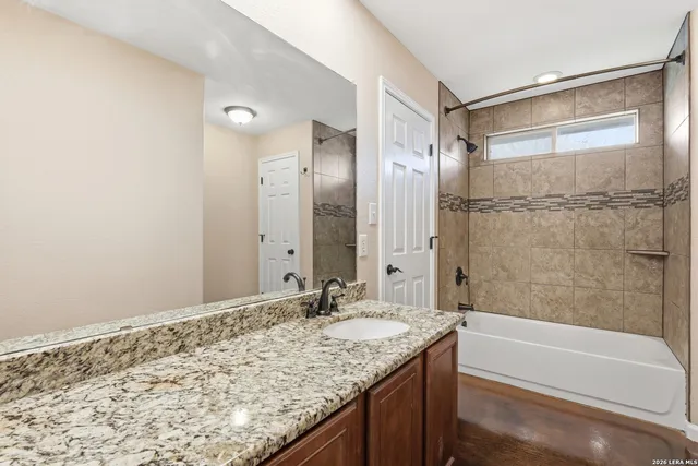 a bathroom with a granite countertop sink and a bathtub