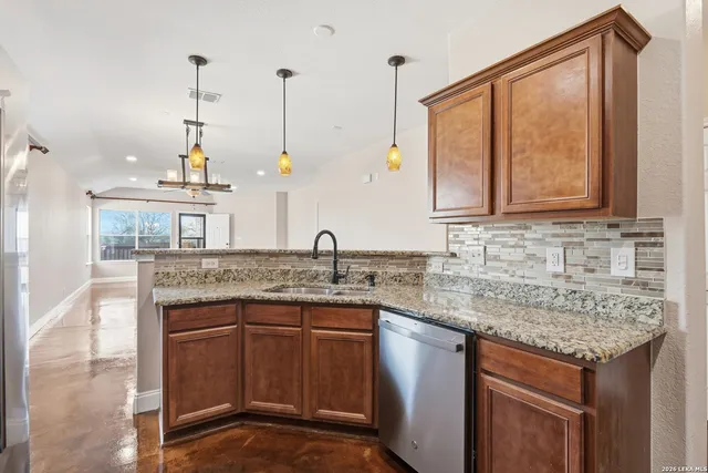 a kitchen with stainless steel appliances granite countertop a sink a stove and a wooden floors