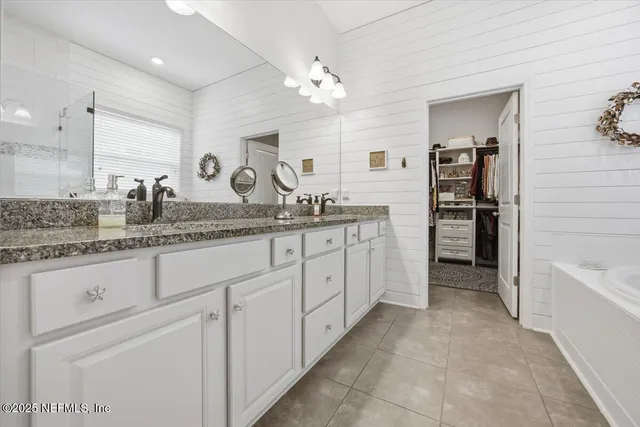 a spacious bathroom with a granite countertop sink a toilet a mirror and bathtub