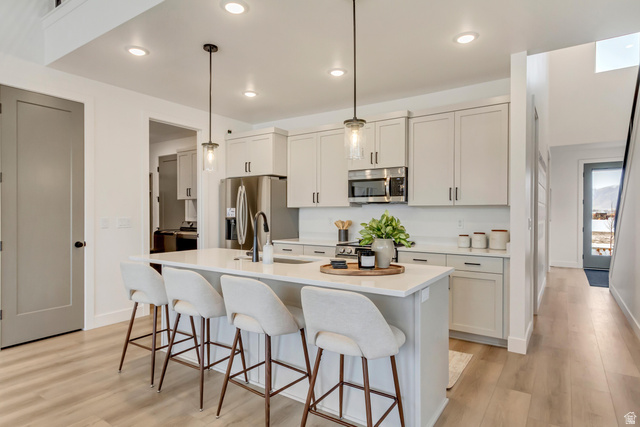 1389 1440 East, Unit 1 Payson, UT 84651 - Photo 3 of 17 Kitchen featuring a central island with countertop seating, light-toned cabinetry, stainless steel appliances, and wood-finish flooring