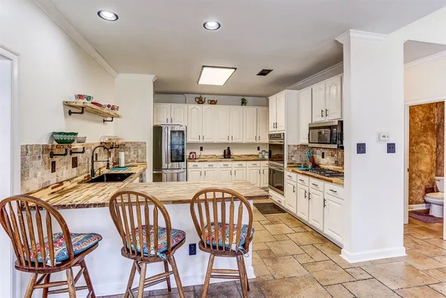 a kitchen with stainless steel appliances granite countertop a refrigerator a stove a sink dishwasher a dining table and chairs with wooden floor