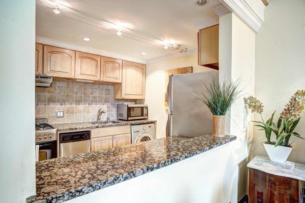 64 Commonwealth Avenue, Unit 3 Boston, MA 02116 - Photo 6 of 10 a kitchen with stainless steel appliances kitchen island granite countertop a refrigerator a stove and a sink