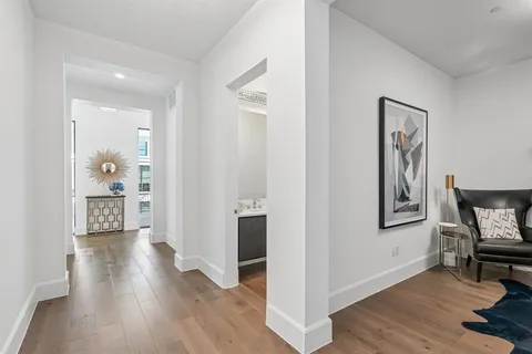 a view of a hallway with wooden floor and a bathroom