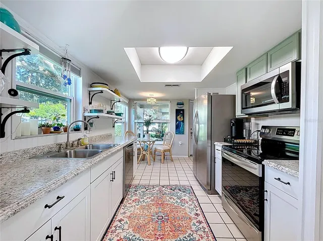 a kitchen with granite countertop stainless steel appliances a stove a sink and a refrigerator