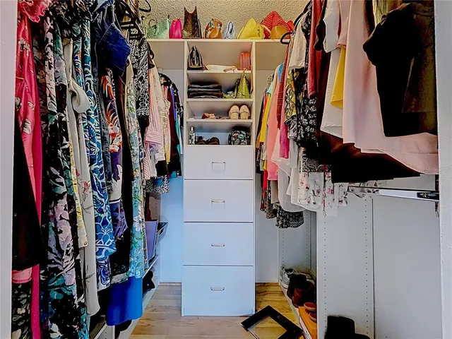 a view of walk in closet with clothes and shoes