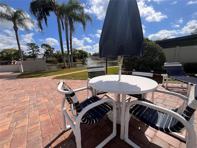 a view of a patio with table and chairs under an umbrella with a fire pit